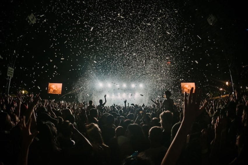Arena crowd with hands up under falling confetti