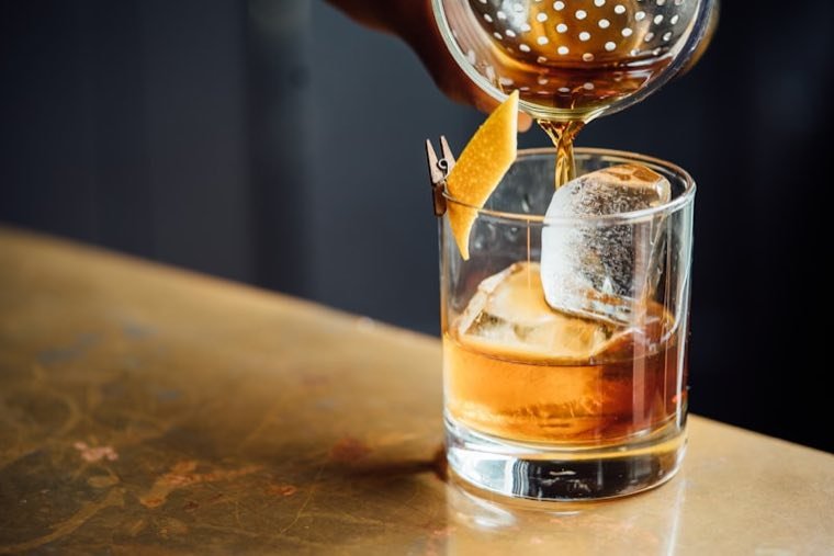 Old fashioned cocktail poured on a brass bar top