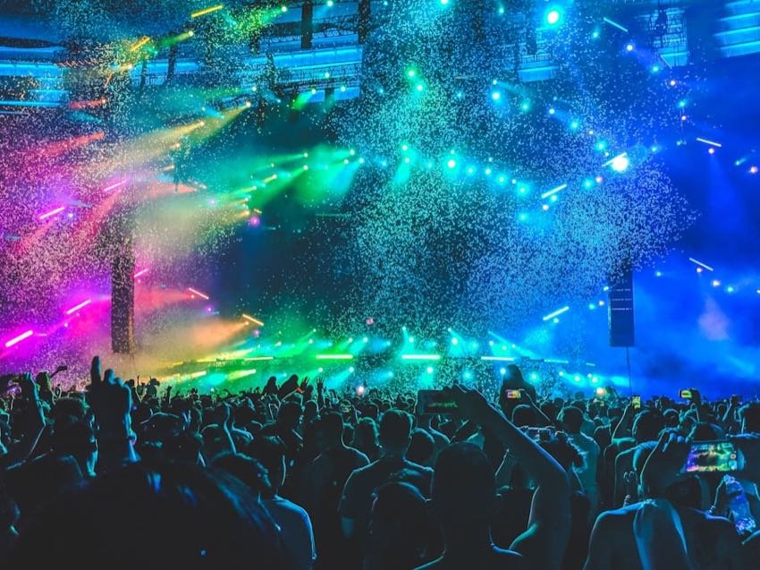 Confetti falling over a packed concert floor in blue light